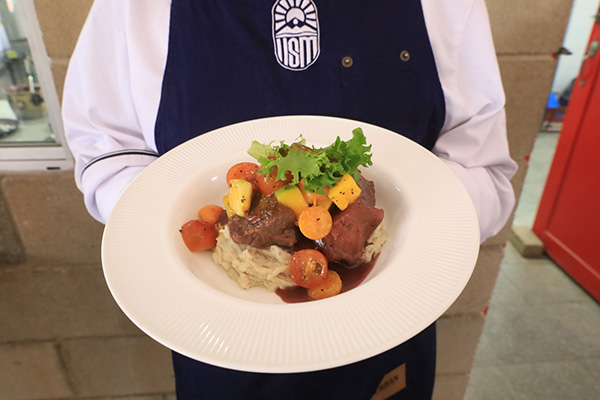 Lomo de res en salsa de corozo, servido sobre puré de cayeye tres quesos y acompañado de una fresca ensalada tropical.