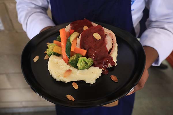  Lomo de cerdo navideño al barril, relleno y bañado en salsa de frutos rojos, sobre una porción de puré de papá y acompañado de vegetales salteados.